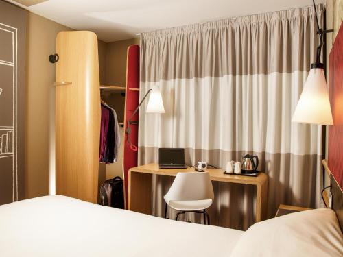 a hotel room with a bed and a desk with a laptop at ibis London Excel-Docklands in London