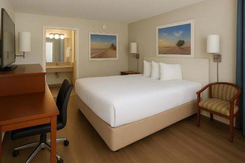a hotel room with a white bed and a desk at Days Inn by Wyndham Bradenton I-75 in Bradenton