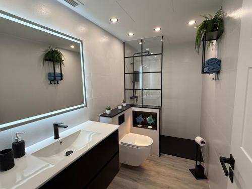 a bathroom with a sink and a toilet and a mirror at La Casita del Mar in Combarro