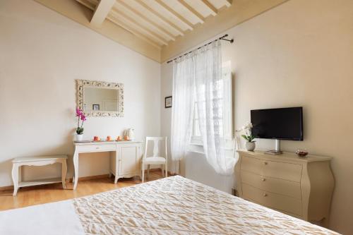 a bedroom with a bed and a dresser with a television at Residenza d'Epoca Relais I Miracoli in Pisa