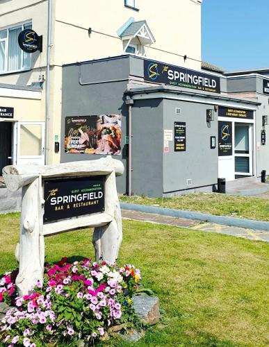 a park bench with flowers in front of a building at The Springfield Hotel in Fairbourne