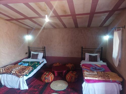 two beds in a room with pumpkins on the floor at Sahara Bedouin camp in Mhamid