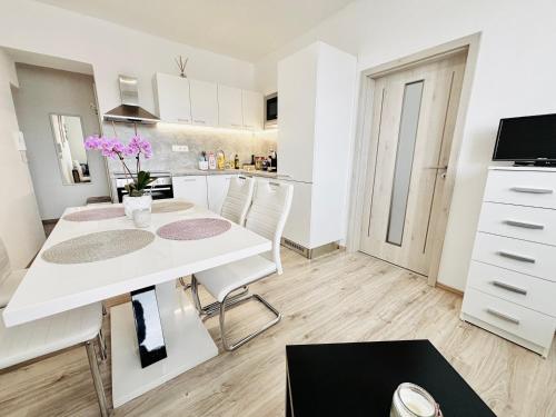 a kitchen and dining room with a white table and chairs at Apartmán u Louckého kláštera 2 plus KK in Znojmo