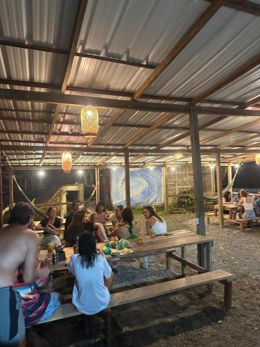 a group of people sitting at picnic tables in a tent at SURF HOUSE ESTILO LIBRE in Buenaventura
