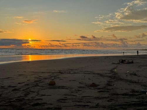 a sunset on a beach with people in the water at SURF HOUSE ESTILO LIBRE in Buenaventura