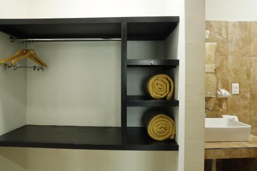 a bathroom with black shelves with yellow towels at Hotel Tamtokow in Ciudad Valles
