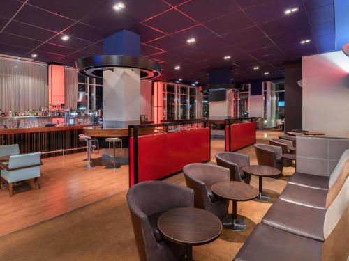 a restaurant with chairs and tables and a bar at Novotel London Excel in London