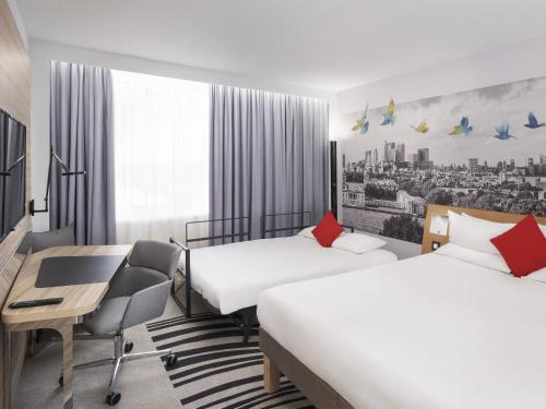a hotel room with two beds and a desk at Novotel London Excel in London