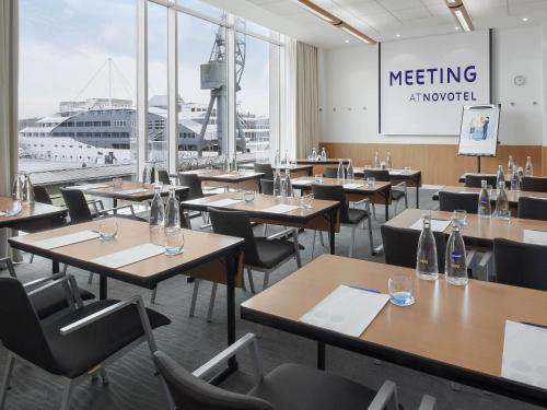 a dining room with tables and chairs and a large window at Novotel London Excel in London