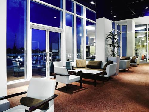 a living room with chairs and tables and windows at Novotel London Excel in London