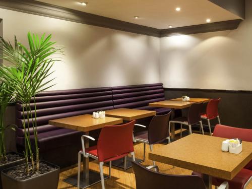 a restaurant with tables and chairs and a bench at ibis Hotel Northampton Centre in Northampton