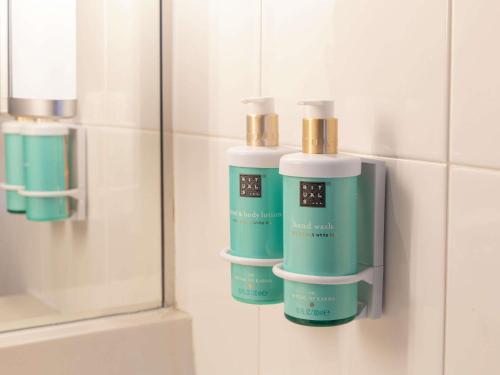 a bathroom with three bottles ofodorizers on a wall at Novotel Barcelona Cornellà in Cornellà de Llobregat