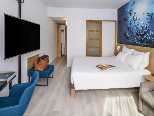 a hotel room with a white bed and a tv at Novotel Barcelona Cornellà in Cornellà de Llobregat