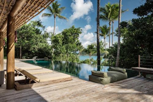a swimming pool with a wooden deck and palm trees at Villa 21 in Itacaré