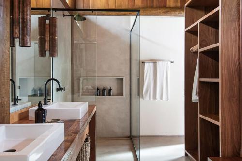 Un baño con ducha de cristal y lavabo. en Villa 21, en Itacaré