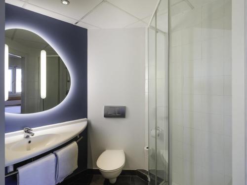 une salle de bain avec un lavabo, des toilettes et un miroir dans l'établissement Ibis Budget Málaga Aeropuerto Avenida de Velazquez, à Malaga