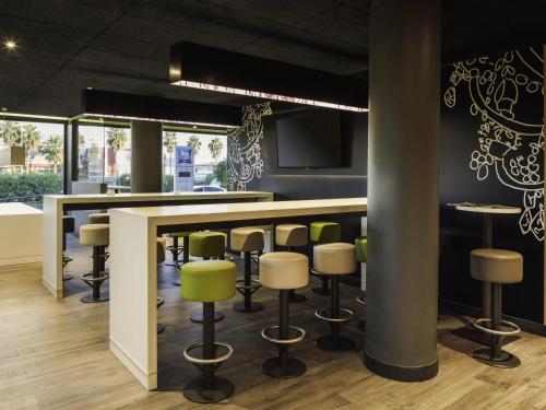 un bar dans un restaurant avec tabourets verts dans l'établissement Ibis Budget Málaga Aeropuerto Avenida de Velazquez, à Malaga