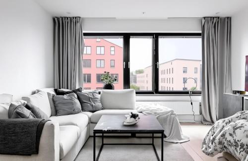 a living room with a white couch and a large window at Aurora Luxe Apartment Växjö Near Vida Arena in Växjö