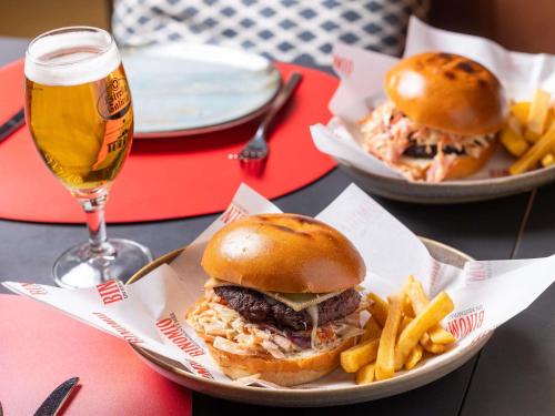 a plate with a sandwich and fries and a glass of beer at Novotel Barcelona Cornellà in Cornellà de Llobregat