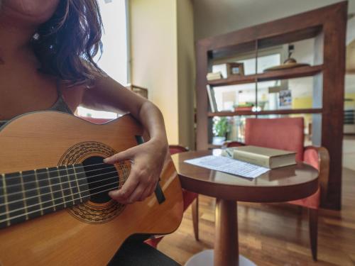 a woman holding a guitar next to a table at Ibis Murcia in Murcia