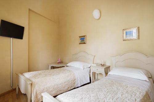 a bedroom with two beds and a flat screen tv at Residenza d'Epoca Relais I Miracoli in Pisa