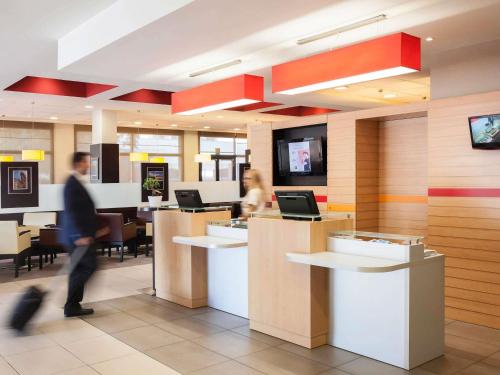 a lobby with people sitting at counters in a restaurant at Ibis Ripollet in Ripollet