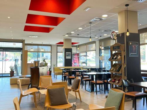 a restaurant with tables and chairs in a cafeteria at Ibis Ripollet in Ripollet