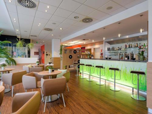 a restaurant with tables and chairs and a bar at ibis Heilbronn City in Heilbronn