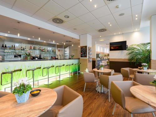 a restaurant with tables and chairs and a bar at ibis Heilbronn City in Heilbronn