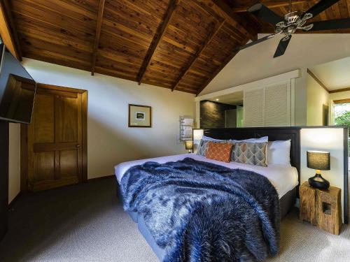 a bedroom with a bed with a blue blanket at Grand Mercure Puka Park Resort in Pauanui