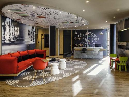 a lobby with a red couch and a table and chairs at Ibis Granada in Granada
