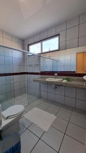 a bathroom with a toilet and two sinks and a window at Le Soleil Pousada e Restaurante in Praia do Frances