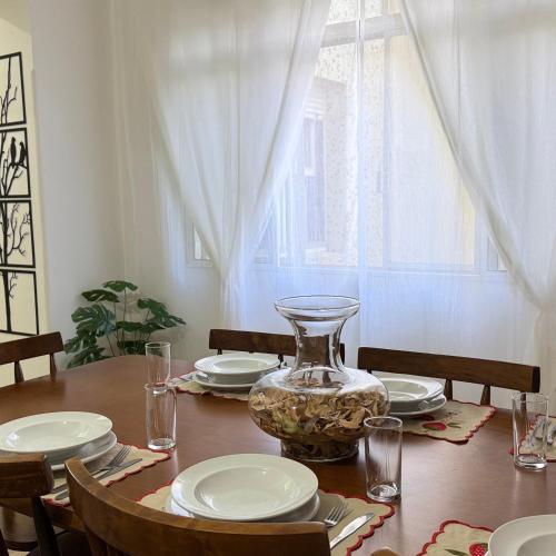 a dining room table with plates and a vase on it at SEO Apê no Centro de Serra Negra -em frente a Rodoviária in Serra Negra