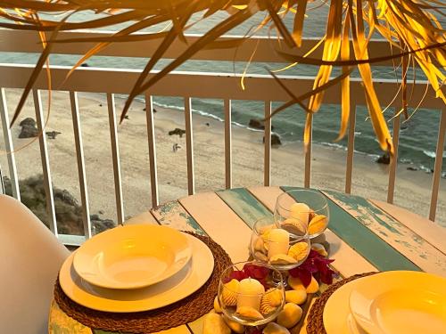 a table with plates and glasses on a balcony with the beach at Estrela do Mar - Ocean View Apartment - Sesimbra - Falésia in Sesimbra