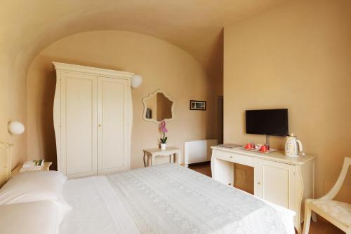 a bedroom with a bed and a desk with a television at Residenza d'Epoca Relais I Miracoli in Pisa