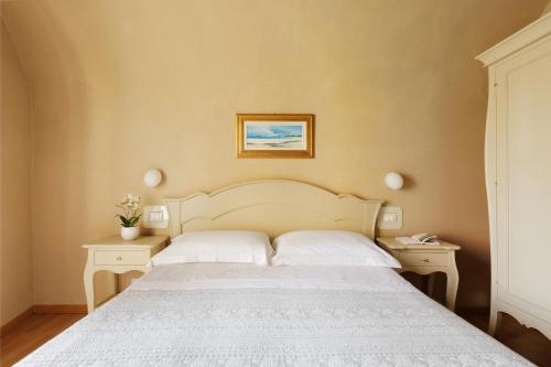 a bedroom with a white bed and two night stands at Residenza d'Epoca Relais I Miracoli in Pisa