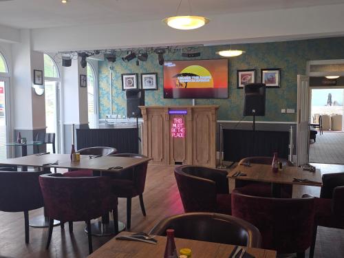 a restaurant with wooden tables and chairs and a stage at The Springfield Hotel in Fairbourne