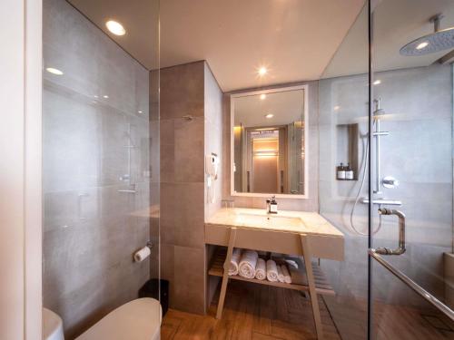 a bathroom with a sink and a shower at Mercure Kuta Bali in Kuta