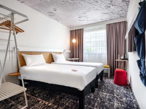 a room with two beds in a hotel room at Hotel Ibis Krakow Centrum in Kraków
