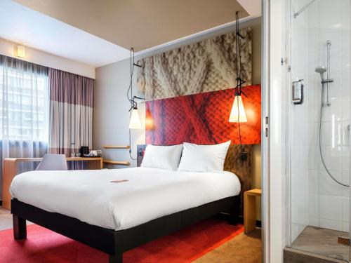 a hotel room with a large bed and a shower at Hotel Ibis Krakow Centrum in Kraków