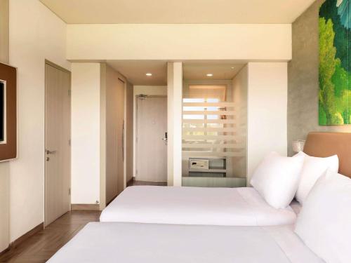 a bedroom with a large white bed with white pillows at Mercure Kuta Bali in Kuta