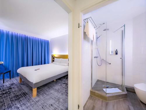 a hotel room with a bed and a shower at Hotel Ibis Krakow Centrum in Kraków