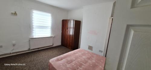 an empty room with a pink ottoman and a window at Lovely house in Luton