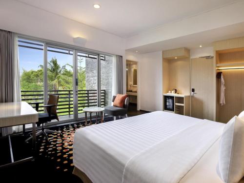a hotel room with a large bed and a balcony at Novotel Palembang in Palembang