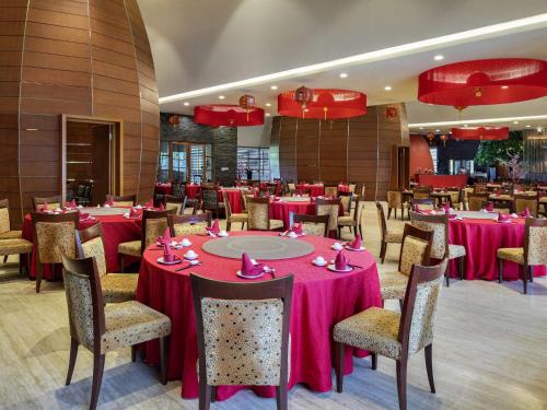 a dining room with tables and chairs with pink tablecloths at Novotel Palembang in Palembang