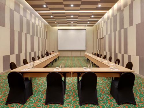 a conference room with tables and chairs and a whiteboard at Novotel Palembang in Palembang