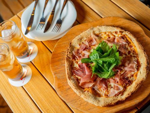 a pizza on a wooden plate on a table with drinks at ibis Sao Paulo Congonhas in Sao Paulo