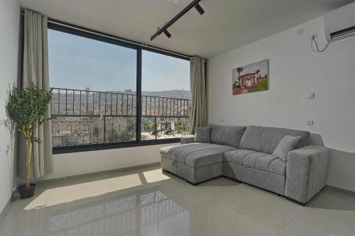 a living room with a couch and a large window at Levication Multiple Apartments - Family Stays Tiberias in Tiberias