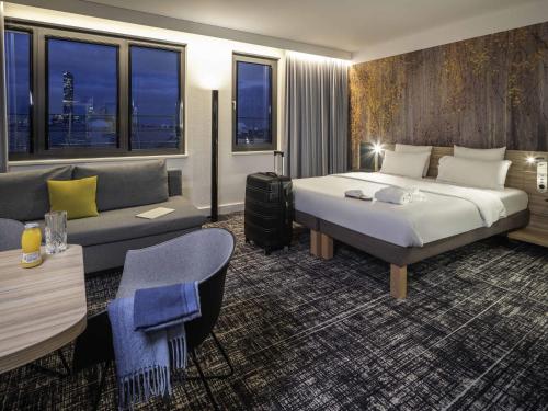 a hotel room with a bed and a couch at Novotel Suites Wien City Donau in Vienna