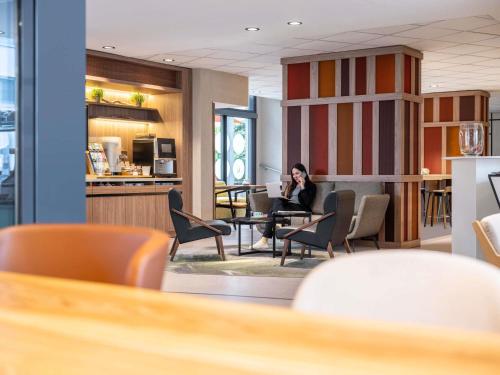 a woman sitting at a table talking on a cell phone at Novotel Suites Wien City Donau in Vienna